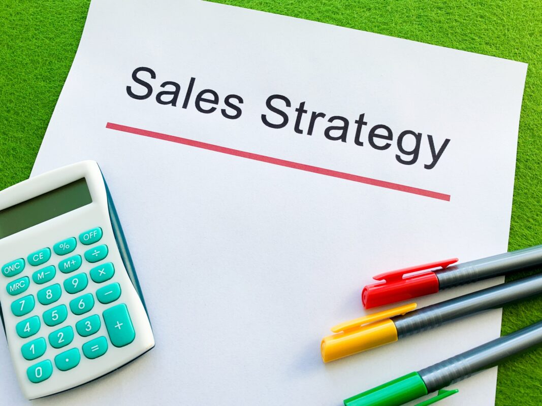Paper with text sales strategy on green background